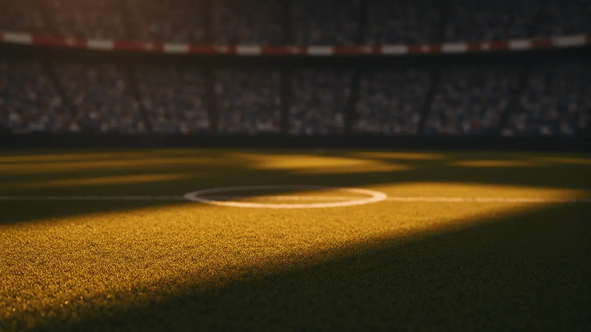 Floodlit stadium pitch at golden hour with dramatic shadows, blurred crowd stands, sky blue and red-white colour tones.