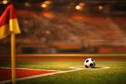 Football pitch under floodlights with ball on penalty spot, red and gold colour tones, empty stadium background, cinematic lighting.