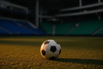 Empty stadium corner with match ball in foreground, lit in French navy and Senegalese green, evening floodlight mood.