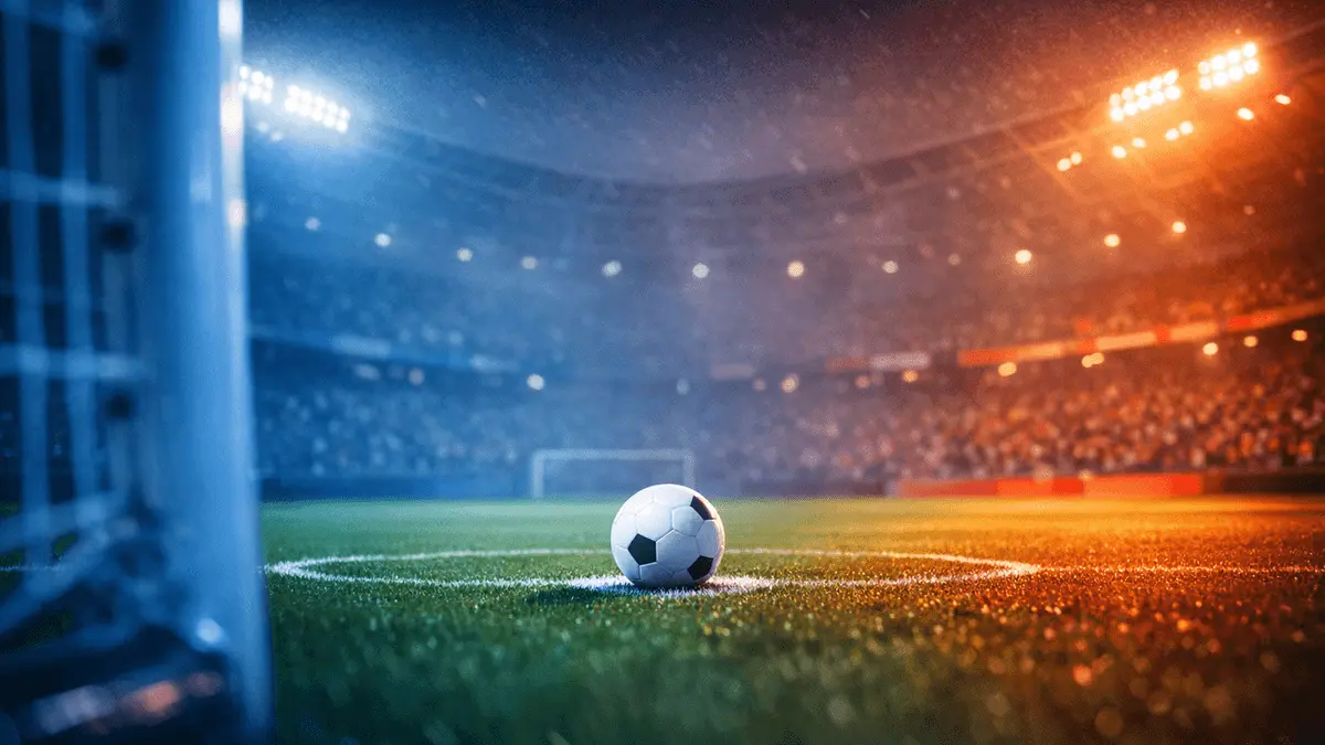 Empty floodlit football pitch at dusk with centre-spot ball, golden and blue lighting, anticipatory stadium atmosphere.