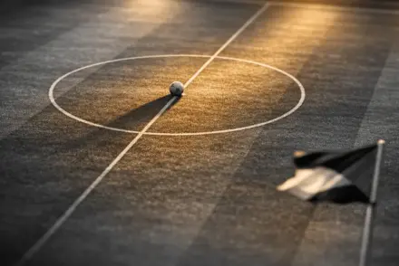 Floodlit football pitch at dusk, centre spot with match ball, golden-hour lighting, black and gold colour grade.