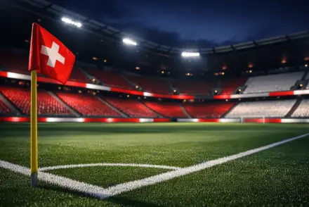 Empty stadium corner section with red-white accent lighting, pitch markings sharp in foreground, evening floodlights