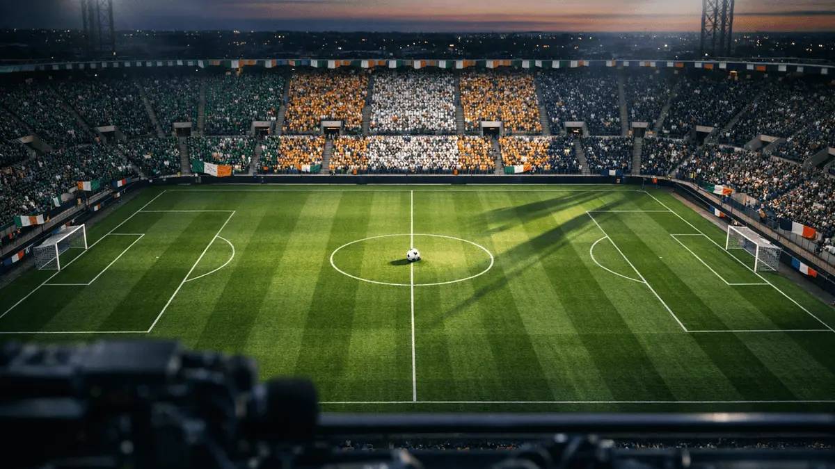Aerial stadium view at dusk with floodlit pitch, coloured bunting, and national flag-hued stand sections.