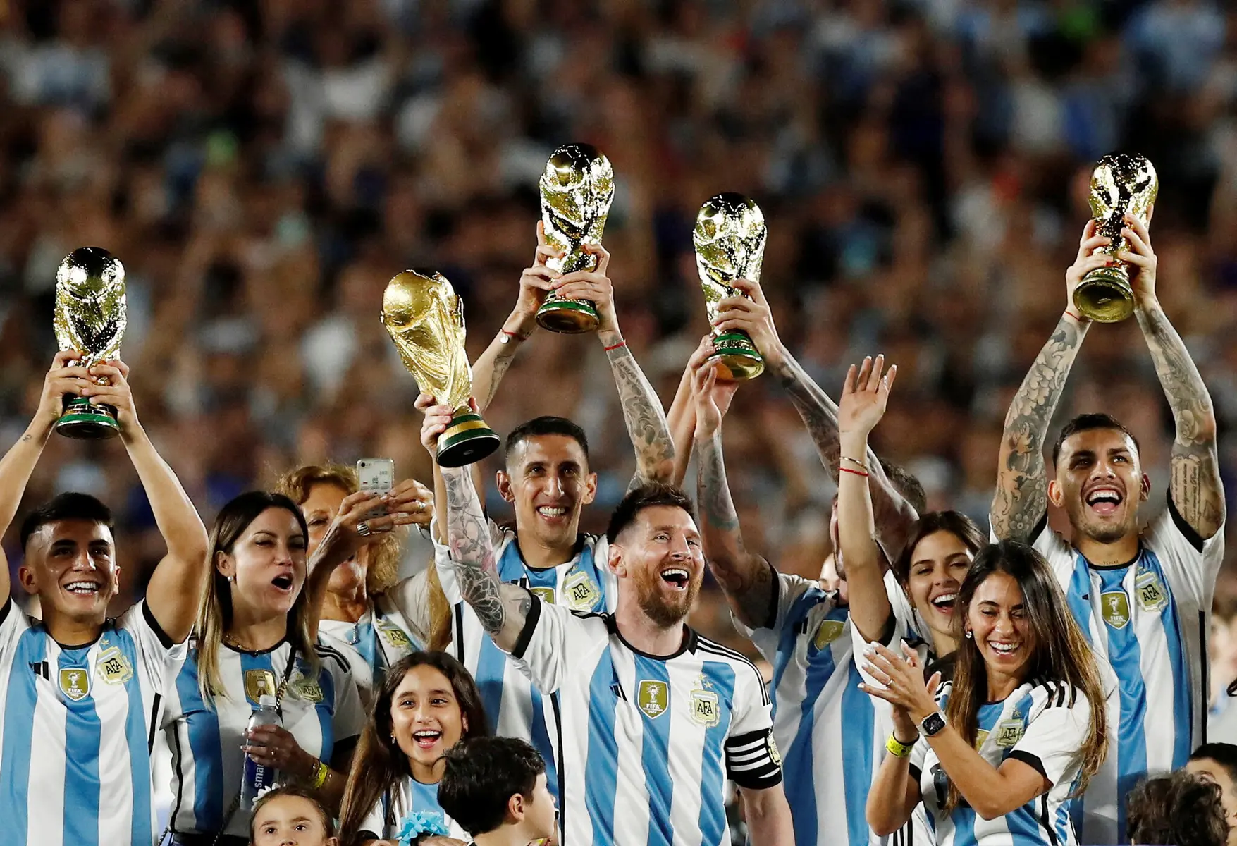 Argentina national football team players celebrating with World Cup trophies.