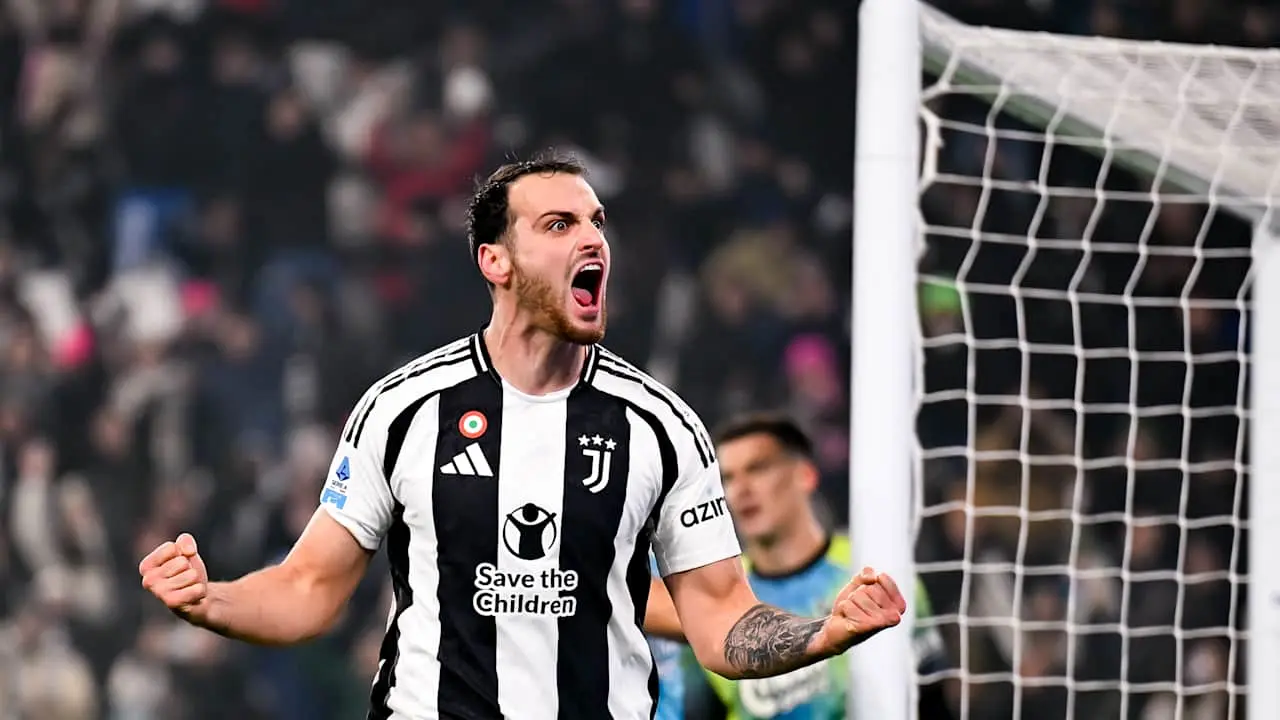 Federico Gatti comemora gol da Juventus em partida com torcedores ao fundo.