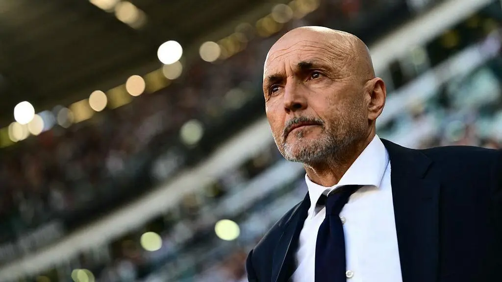 Close-up portrait of Luciano Spalletti wearing a dark suit and tie in a football stadium