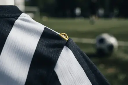 Black and white striped football jersey with gold accent detail in dramatic lighting