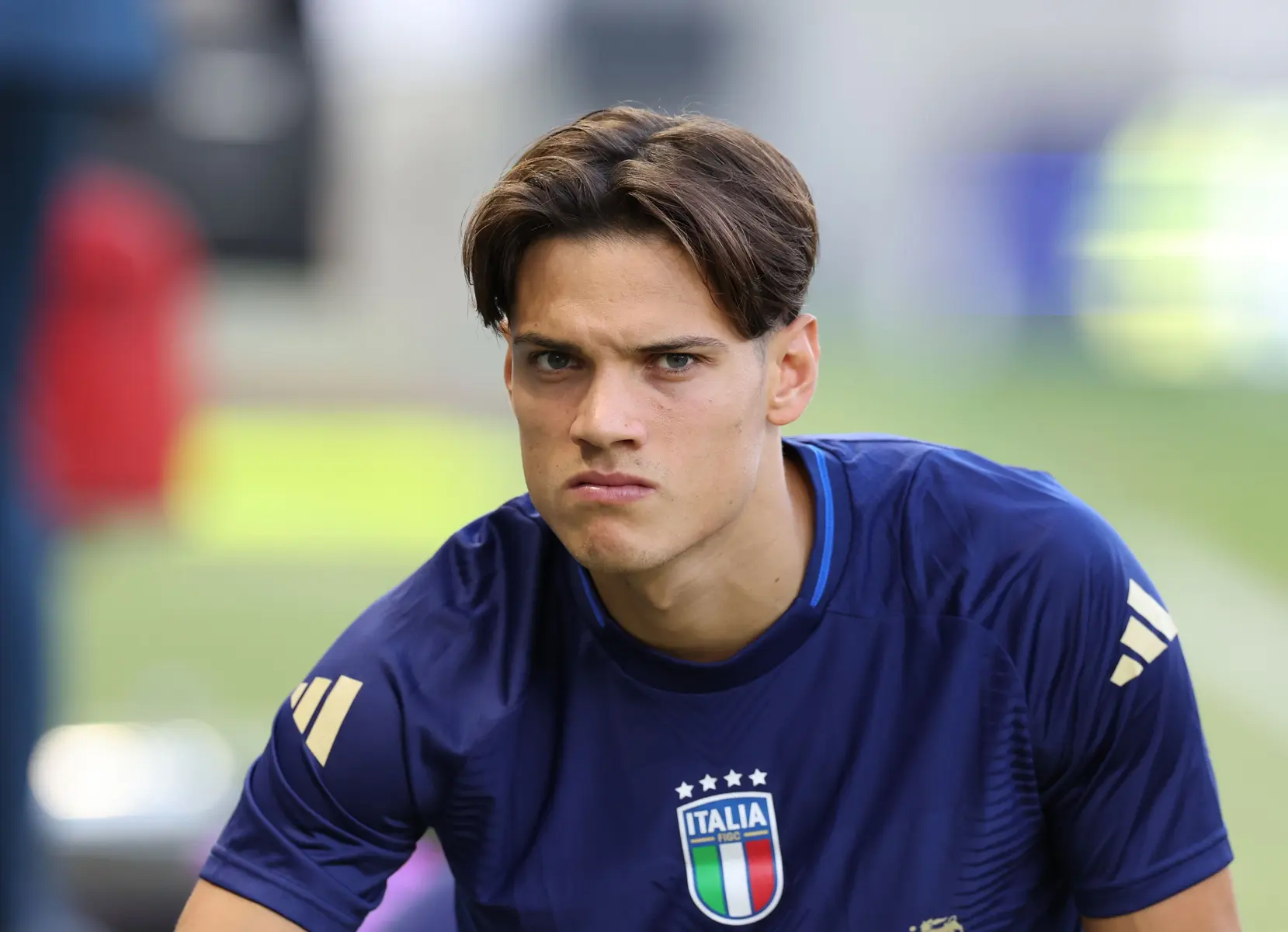 A focused male football player wearing an Italian national team jersey.