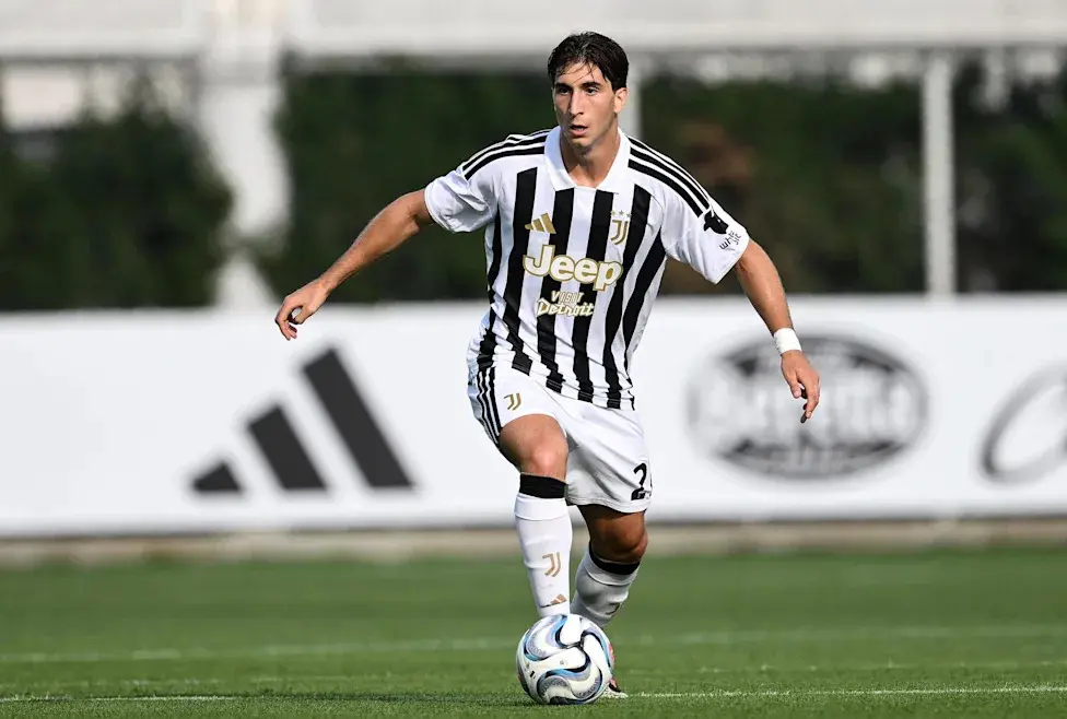Fabio Miretti com o uniforme da Juventus driblando uma bola de futebol em um campo gramado