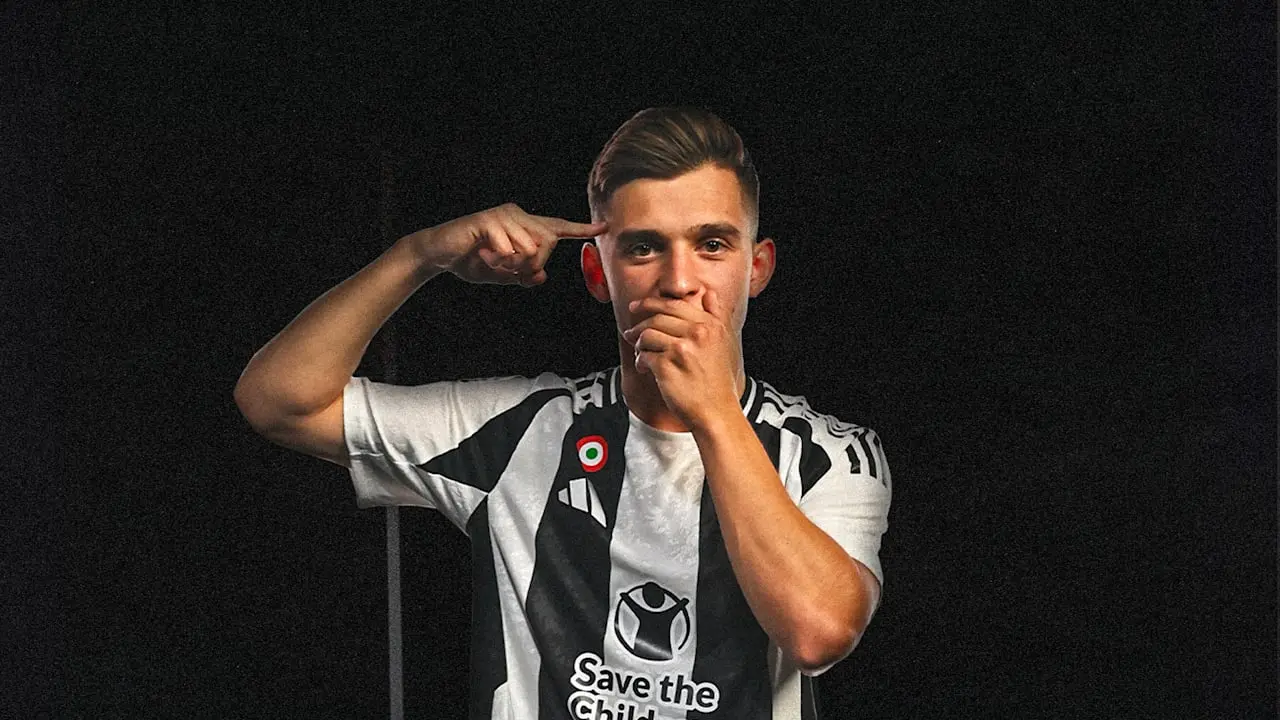 Francisco Conceição wearing a black and white striped Juventus jersey against a black background