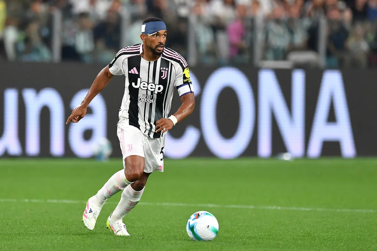 Gleison Bremer in a black and white striped Juventus jersey playing a soccer match on a grass field