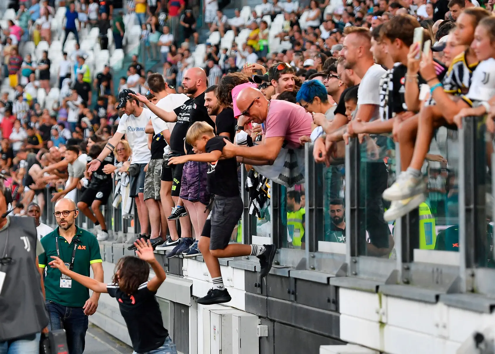 Fans including a young boy jumping over a railing onto the pitch at Juventus Allianz Stadium