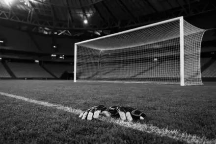 Goalkeeper gloves beside an empty football goal, symbolizing Juventus facing a roadblock in the Unai Simón chase.