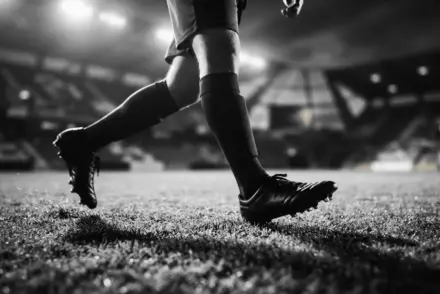 Football player boots on stadium turf in dramatic black and white lighting