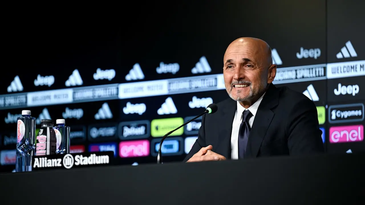 Luciano Spalletti smiling at a press conference with Juventus and Allianz Stadium branding in the background