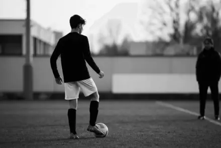 Young Juventus-bound playmaker training under guidance on a monochrome football pitch