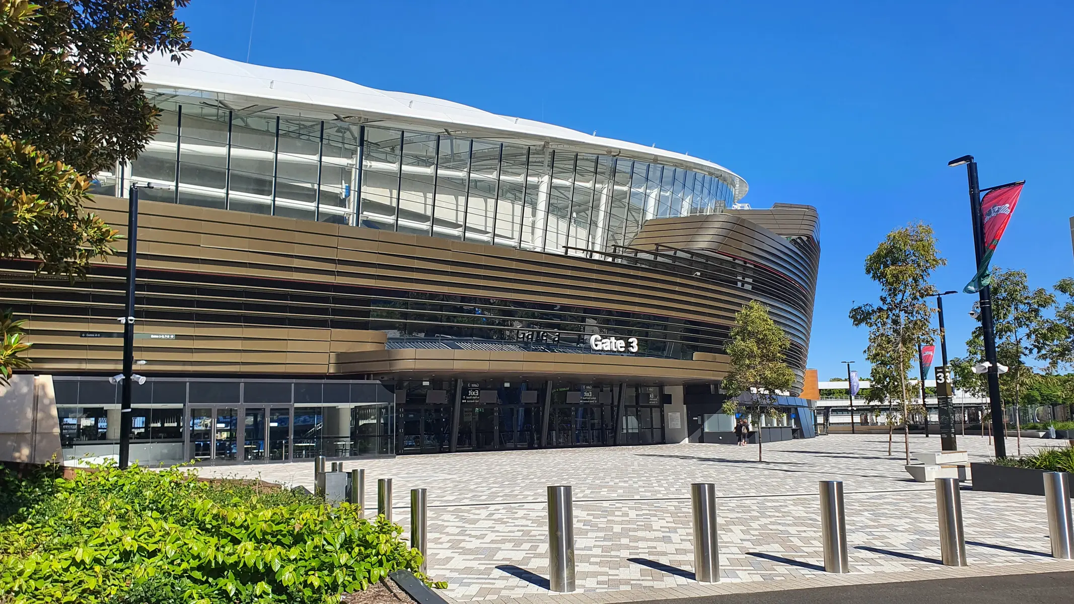 The exterior of Allianz Stadium showing Gate 3 and the surrounding pedestrian plaza under a clear blue sky.