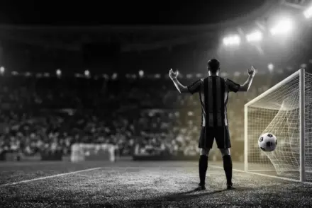 Anonymous Juventus player celebrates a decisive European victory beside the goal under stadium floodlights