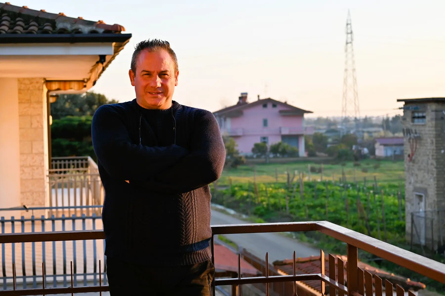 Portrait of Luciano Spalletti standing on a balcony with arms crossed, wearing a dark blue sweater