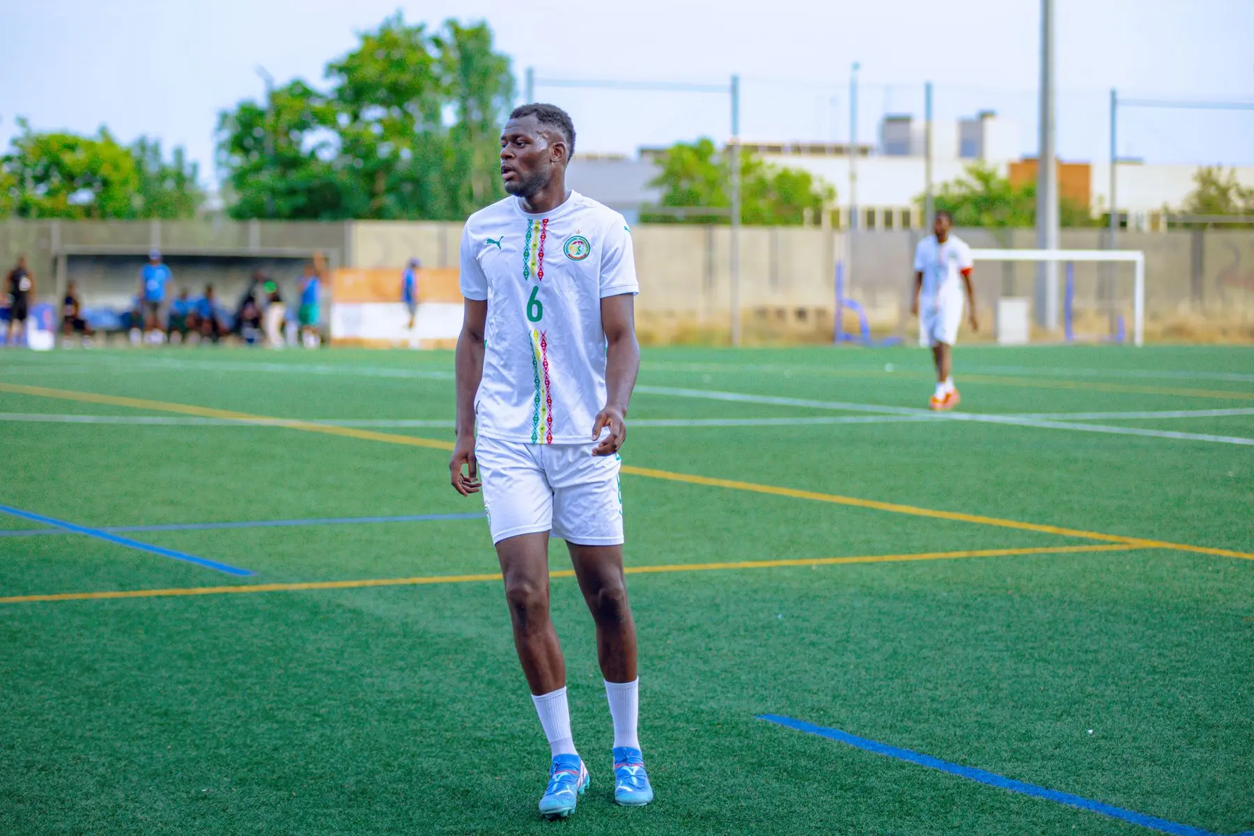 Pape Matar Sarr wearing a white Senegal national team kit on a green football pitch